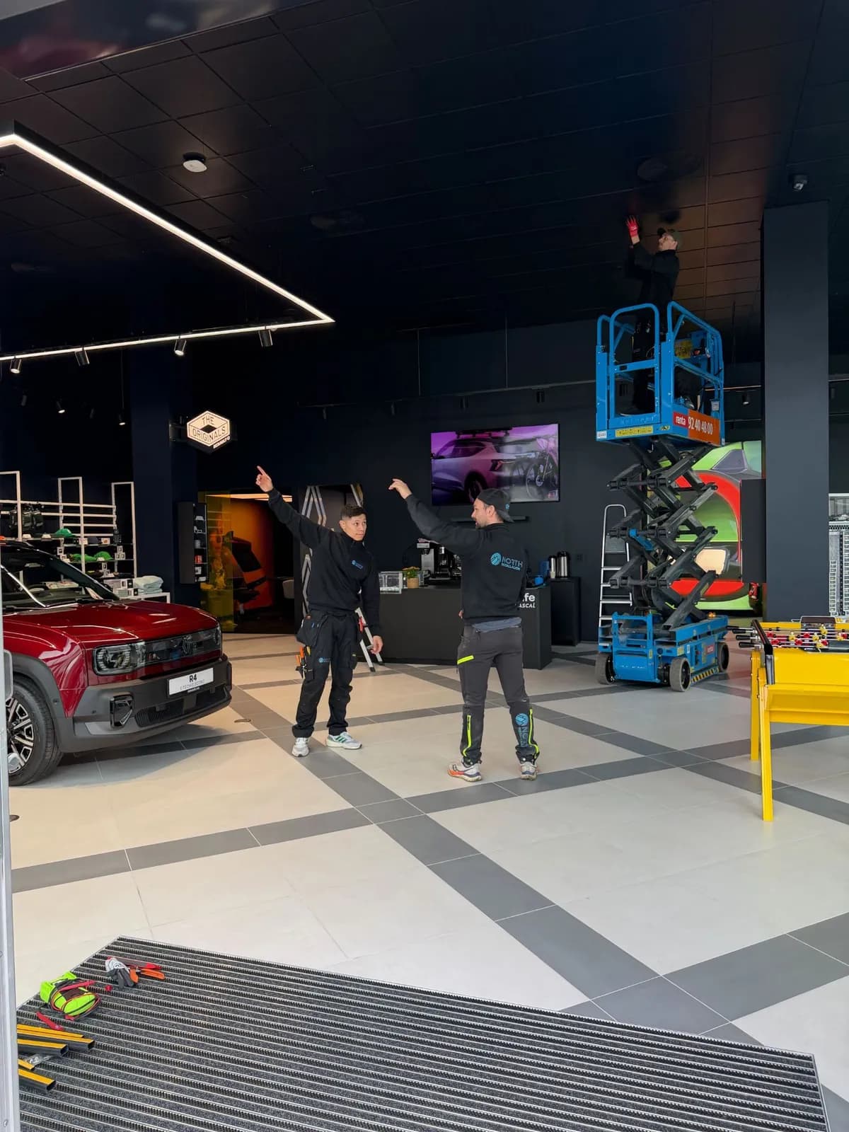 Elektrikere fra North Installasjon monterer belysning fra en lift i et showroom